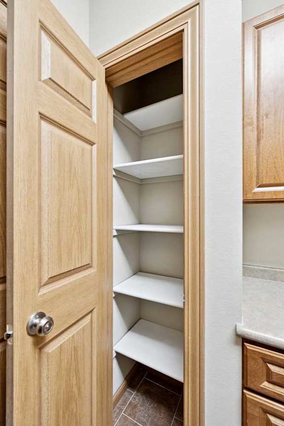 Pantry closet with built-in shelving and wood door for additional kitchen storage.