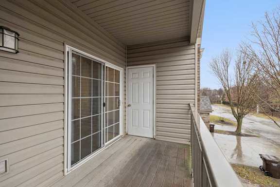 Private balcony with sliding glass door entry, exterior storage closet, and views of the apartment community grounds.