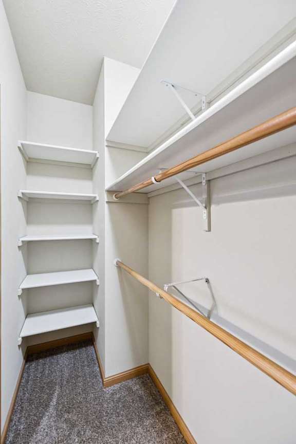 Walk-in bedroom closet with built-in shelving and dual hanging rods for organized storage.