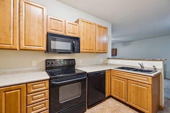 Kitchen with black oven, built-in microwave, dishwasher, and double-basin sink with laminate countertops.