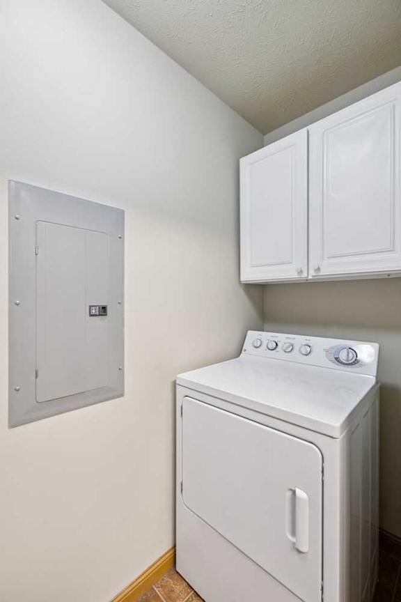 In-unit laundry area with full-size washer and dryer, plus overhead white storage cabinets.
