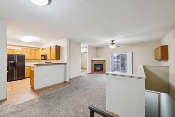 Open-concept living and kitchen area with breakfast bar, black appliances, and sliding glass door to balcony.