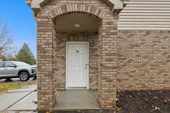 Brick apartment exterior with covered arched entry and private front door.