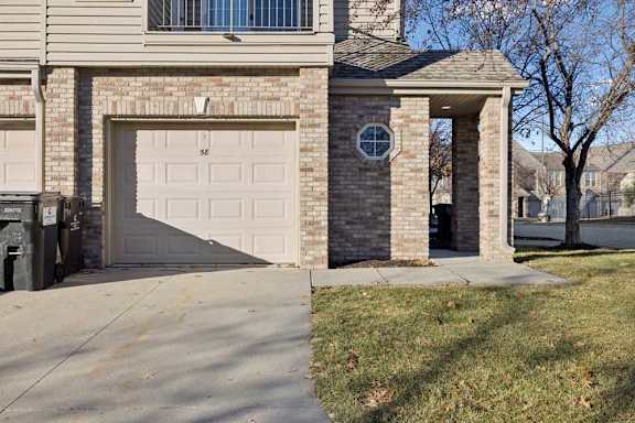 Brick apartment exterior with attached garage, covered entryway, and upper-level balcony above.