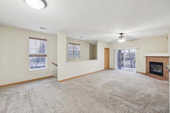Spacious living room with ceiling fan, sliding glass door to private balcony, and corner gas fireplace.