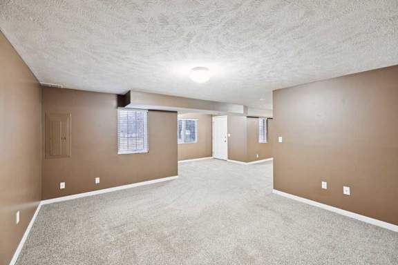Large lower-level rec room with support columns, ample wall space, and egress windows for natural light.
