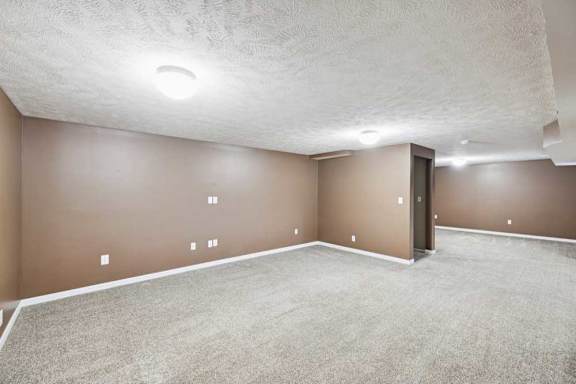Basement family room featuring wide open floor plan and bright overhead lighting.