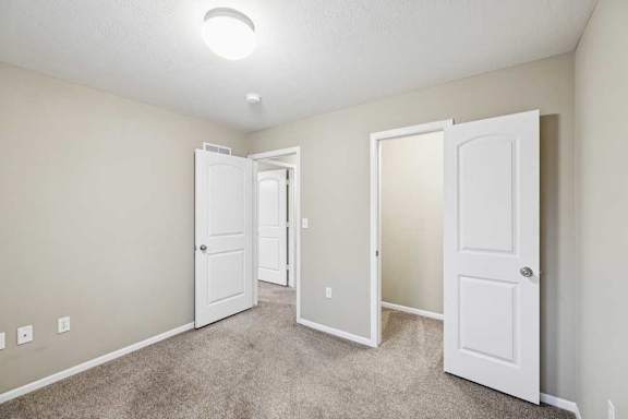 Bedroom with neutral carpet, double-door closet, and adjacent hall access.