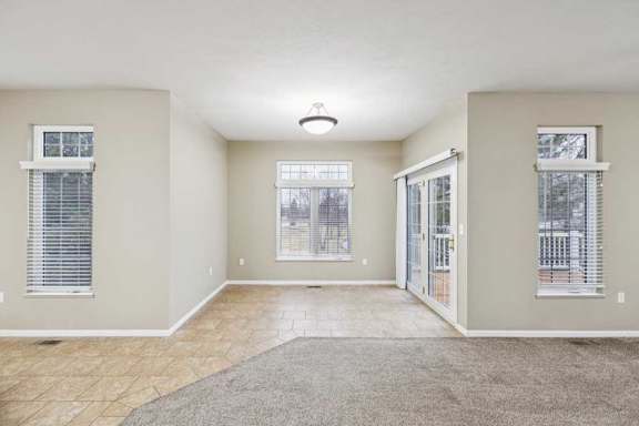 Dining area with tile flooring, large windows, and sliding glass door to deck.