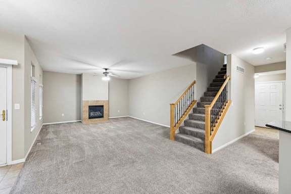 Spacious living room with plush carpet, staircase with wood railing, and gas fireplace.