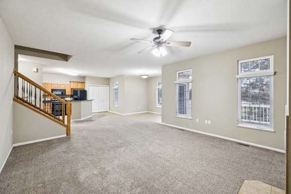 Bright living area with ceiling fan, multiple windows, and open sightlines to kitchen.