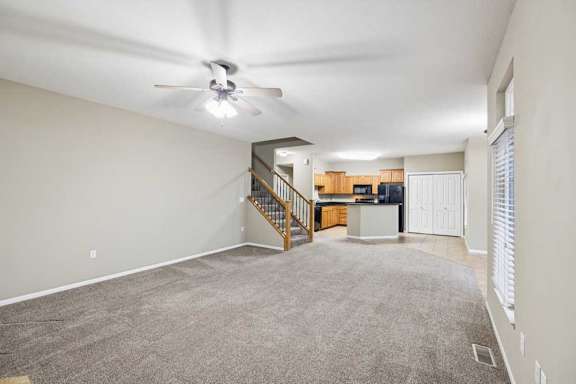 Expansive open-concept apartment interior with carpeted living space, tile entry, and peninsula kitchen.