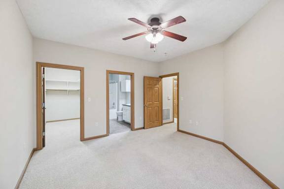 Primary bedroom with ceiling fan, en-suite bathroom access, and large walk-in closet through separate doorways.