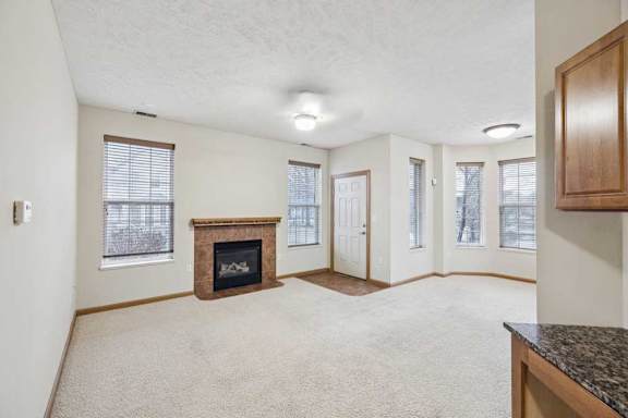 Spacious living room with gas fireplace, multiple windows for natural light, and neutral carpet.