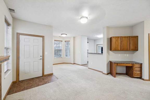 Open-concept living and dining area with built-in desk, upper cabinets, and breakfast bar.