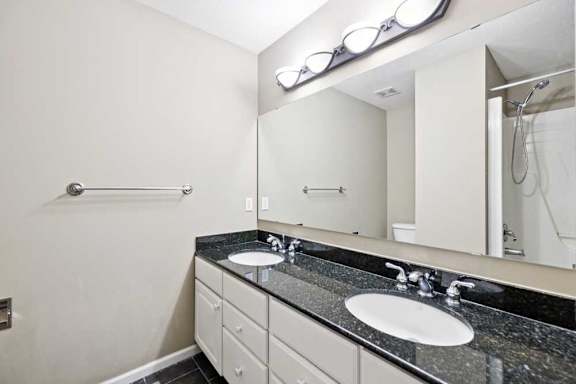 Full bathroom with double-sink vanity, granite countertop, large mirror, and tub and shower combination.