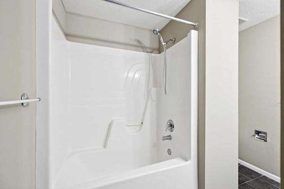 Tub and shower combination with built-in surround and chrome fixtures.