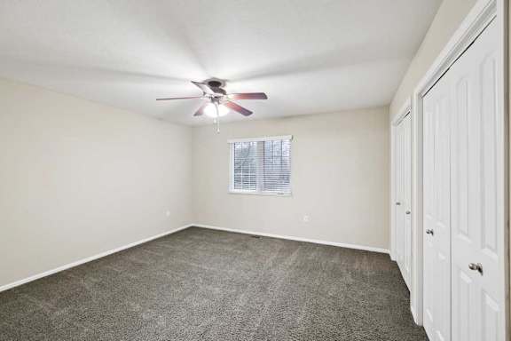 Bedroom with ceiling fan, double-door closet, and neutral finishes.