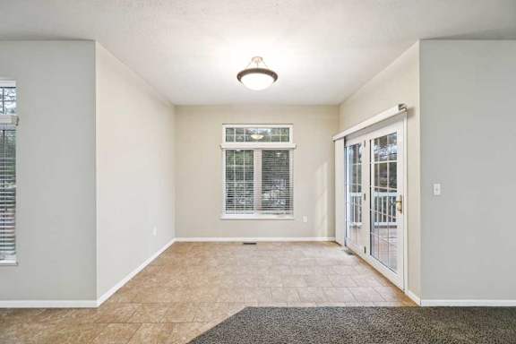 Dining area with tile flooring, large window, and French doors leading to deck.
