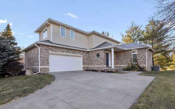 Front duplex exterior with brick facade, attached two-car garage, covered entry, and concrete driveway.