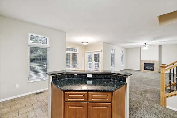 Open-concept view from kitchen peninsula overlooking dining area, living room, and fireplace.