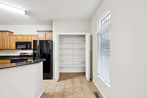 Walk-in pantry with built-in shelving and tile flooring near kitchen.