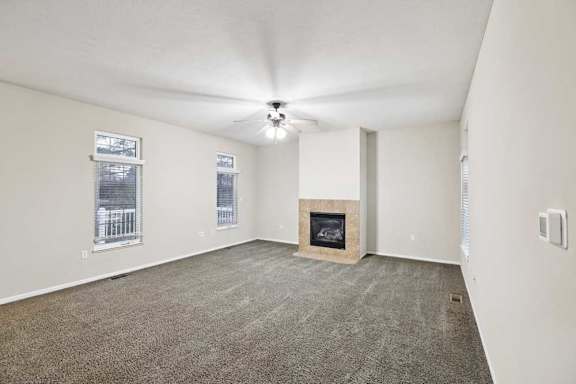 Living room with corner gas fireplace, tall windows, and wall-mounted thermostat.