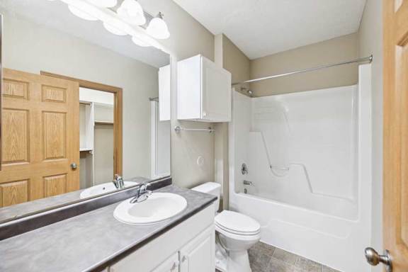 Full bathroom with single-sink vanity, large mirror, linen cabinet, and tub-shower combination.