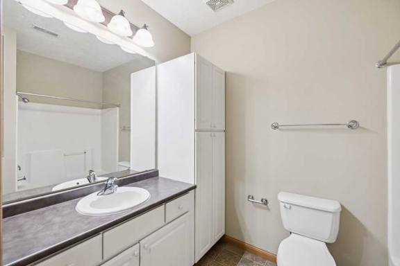 Bathroom vanity with extended countertop, white cabinetry, and wall-mounted storage cabinet.