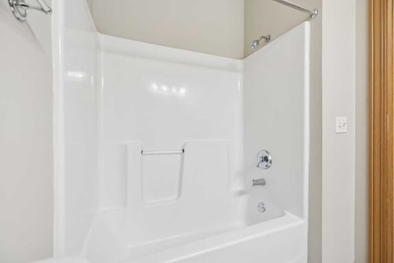 Tub and shower combination with built-in shelving and chrome fixtures.