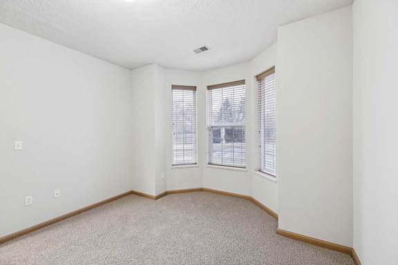 Bedroom featuring bay-style windows, plush carpet, and natural light.