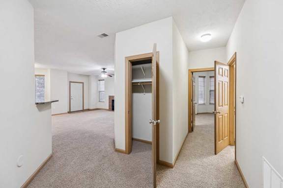 Interior hallway with closet storage connecting kitchen, living room, and bedroom areas.