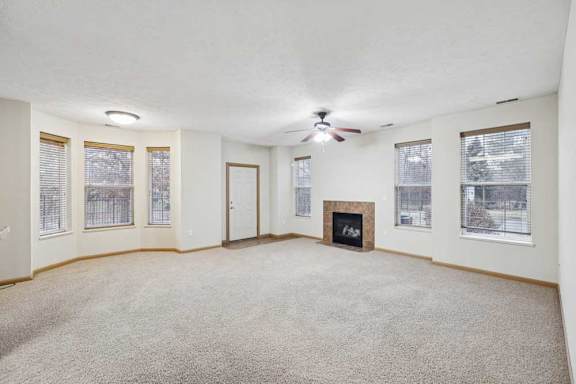 Bright living area with multiple windows, neutral finishes, and fireplace with tile surround.