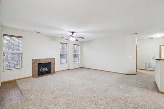 Open-concept apartment living space with ceiling fan, large windows, and breakfast bar overlooking the kitchen.