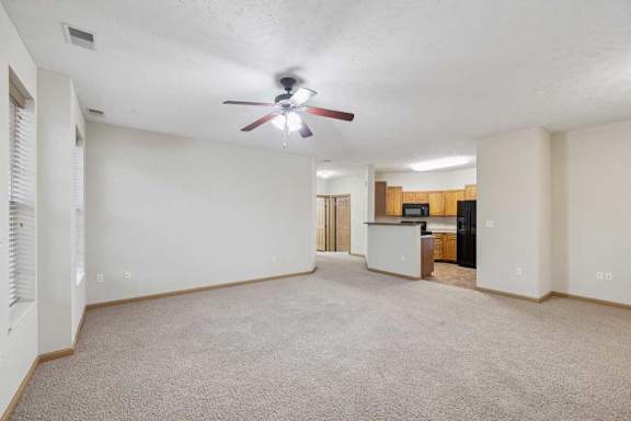 Expansive living and dining area with carpet flooring and open kitchen layout in the background.