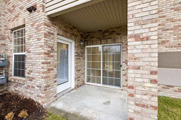 Covered patio entrance with brick façade, exterior light fixture, and sliding glass door access.
