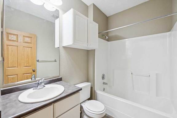 Full bathroom with tub and shower combination, single-sink vanity, wall cabinet, and large mirror with overhead lighting.