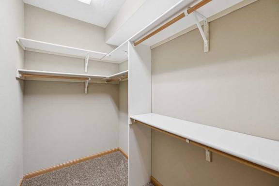 Walk-in closet with built-in shelving, hanging rods, and carpet flooring for organized storage.