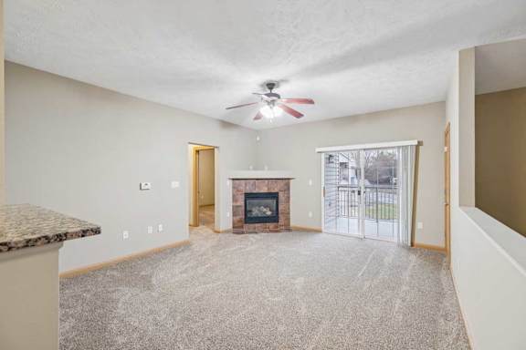 Spacious living room with ceiling fan, corner tile-surround fireplace, and sliding glass door leading to a private balcony.