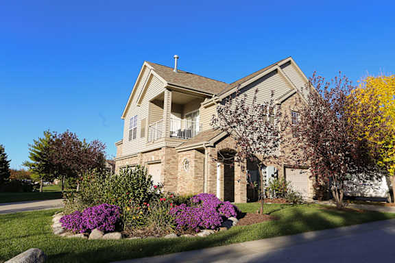 the front of a villa building with a yard with purple flowers