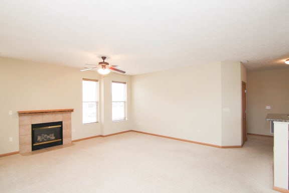 an empty living room with a ceiling fan and a fireplace