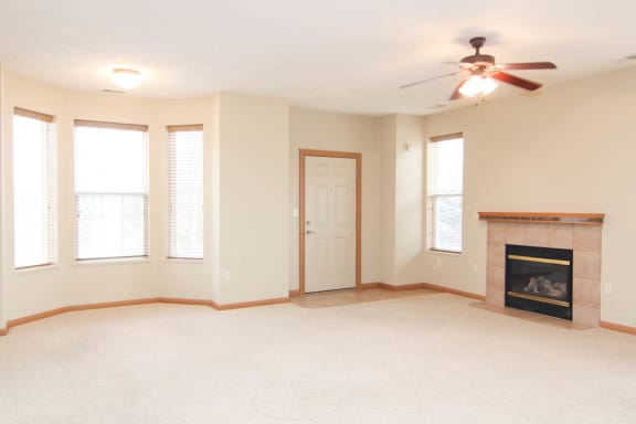 an empty living room with a fireplace and a ceiling fan