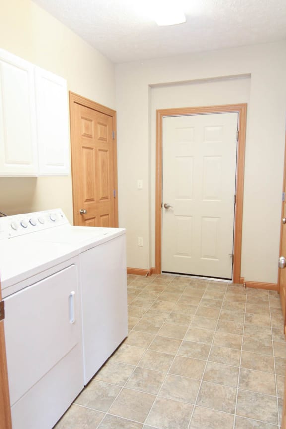 an empty laundry room with a white washer and dryer