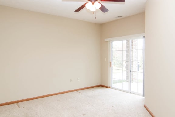 an empty living room with a ceiling fan