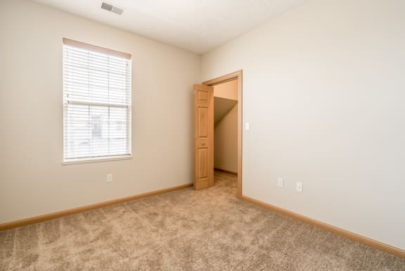 an empty bedroom with a door to a closet and a window