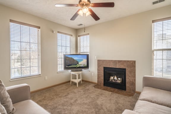 Living room with view of fireplace, ceiling fan and large windows