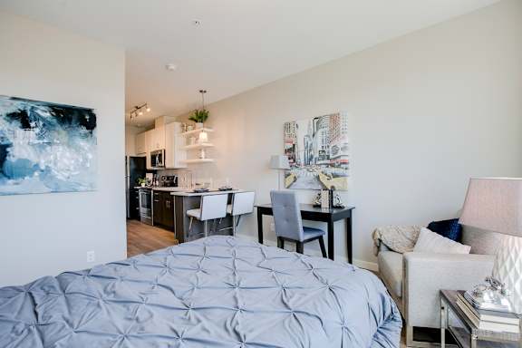 a bedroom with a bed and a kitchen with a table and chairs