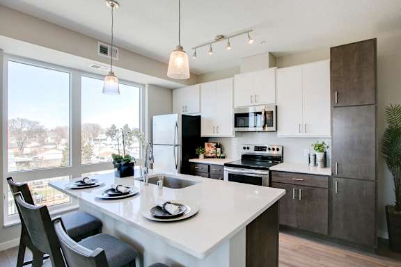 View of kitchen with white and dark contemporary cabinets and quartz countertops at The Central apartments near downtown Minneapolis MN 55408