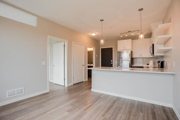 A kitchen with a white counter and wooden floors.