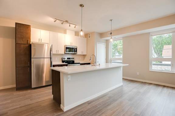A kitchen with a stainless steel refrigerator and microwave above the counter.